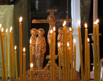 Brennende Kerzen vor einem Kreuz